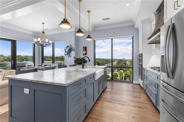 kitchen with a center island with sink, stainless steel appliances, sink, and a healthy amount of sunlight