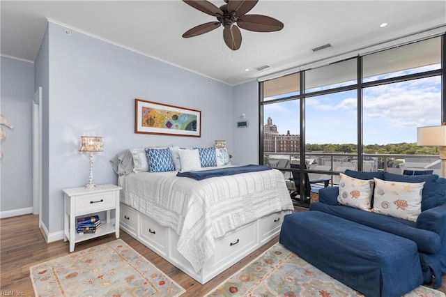 bedroom with wood-type flooring, crown molding, ceiling fan, and expansive windows