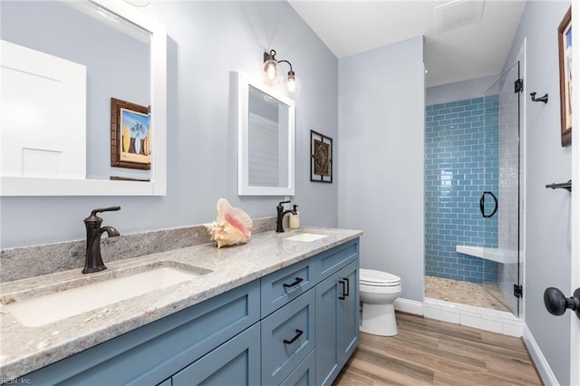 bathroom with toilet, vanity, hardwood / wood-style floors, and a shower with shower door