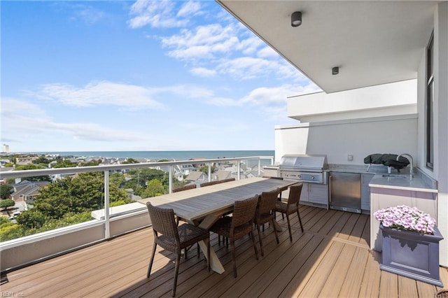 deck with a water view, a grill, a view of the beach, exterior kitchen, and sink