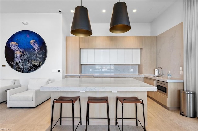 kitchen featuring white cabinets, sink, pendant lighting, and a breakfast bar