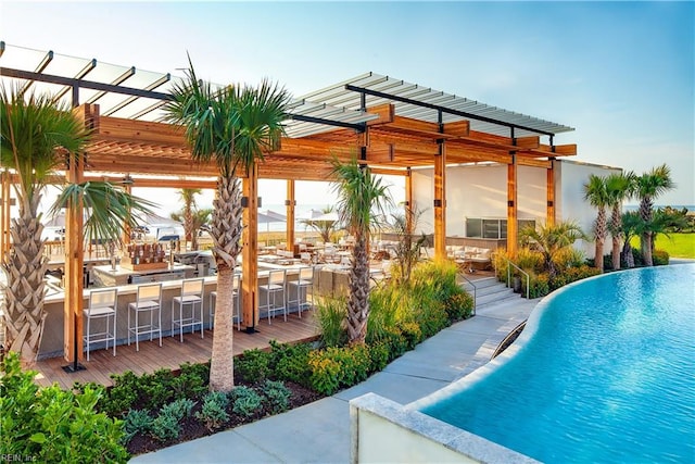 view of swimming pool with a pergola, an outdoor kitchen, and an outdoor bar