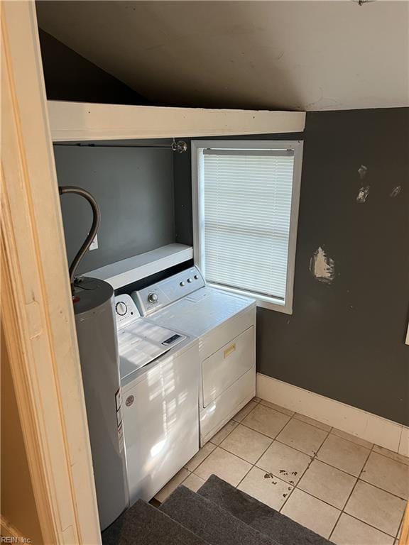 laundry area with light tile patterned flooring, water heater, and washing machine and dryer