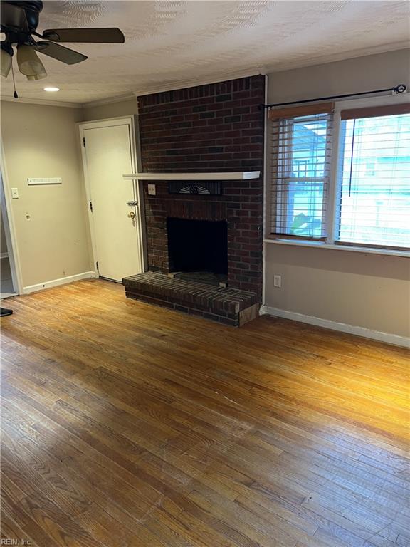 unfurnished living room featuring ceiling fan, a textured ceiling, a fireplace, and hardwood / wood-style floors