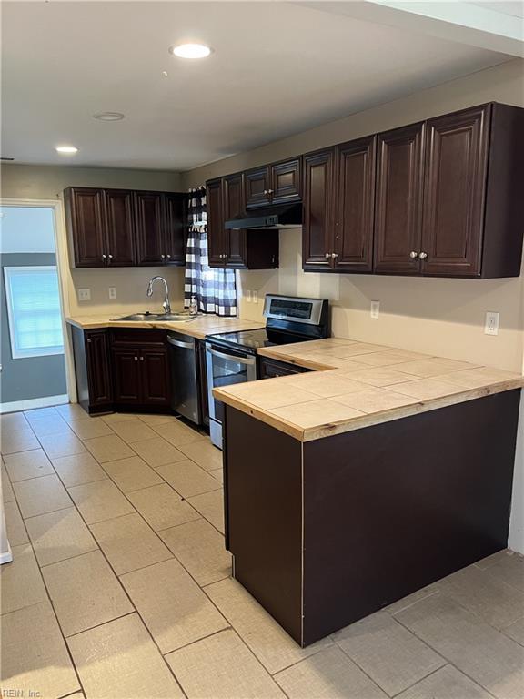 kitchen with dark brown cabinets, light tile patterned flooring, sink, and stainless steel appliances