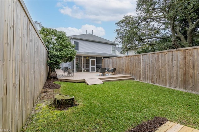 rear view of house featuring a wooden deck, a sunroom, and a yard