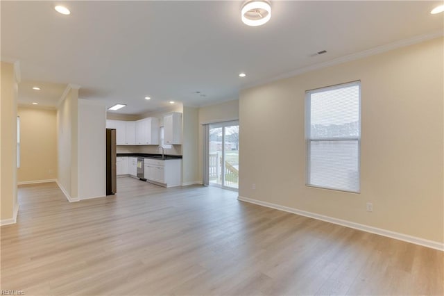 unfurnished living room with crown molding, sink, and light hardwood / wood-style flooring