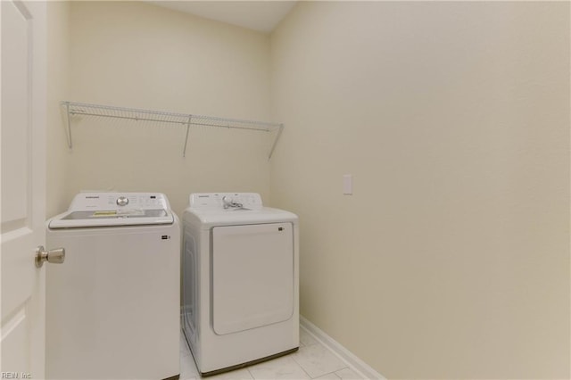 clothes washing area featuring light tile patterned flooring and separate washer and dryer