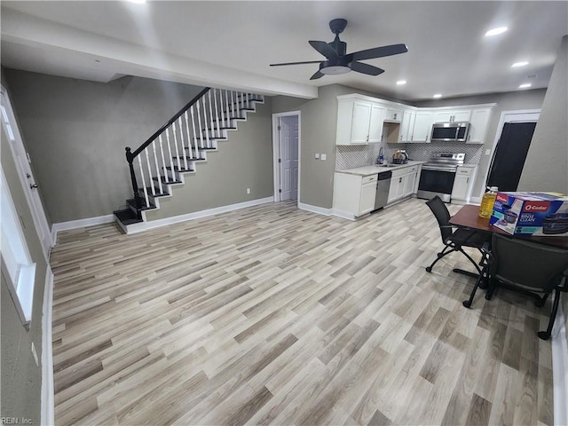 kitchen with ceiling fan, tasteful backsplash, white cabinetry, stainless steel appliances, and light hardwood / wood-style floors