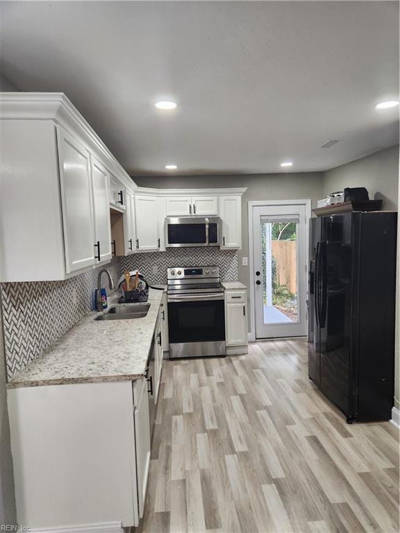 kitchen with appliances with stainless steel finishes, light wood-type flooring, sink, and white cabinetry