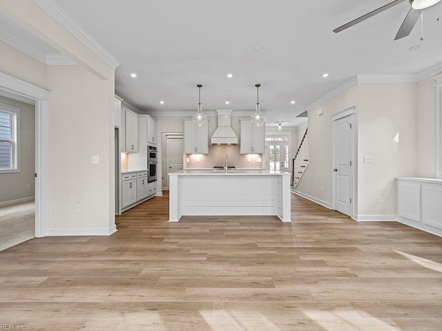 kitchen with ornamental molding, a sink, tasteful backsplash, light countertops, and custom exhaust hood