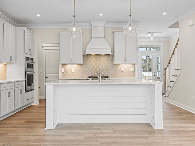 kitchen featuring light wood-style flooring, double oven, light countertops, and premium range hood