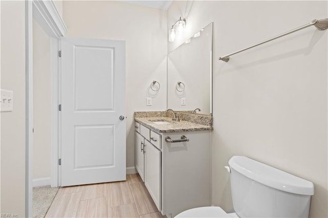 bathroom with vanity, toilet, and baseboards