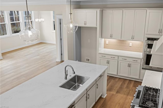 kitchen with wood finished floors, a sink, white cabinets, double oven, and decorative light fixtures