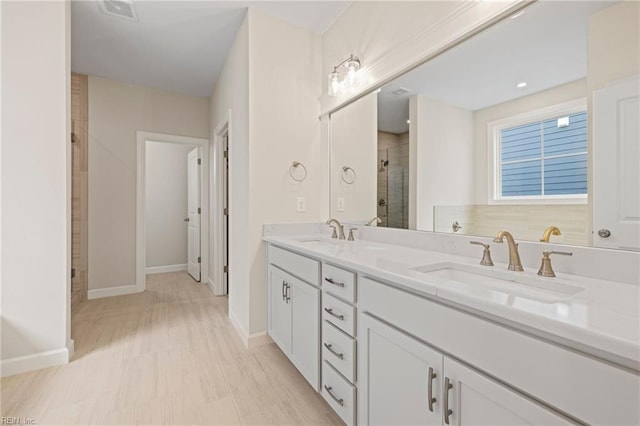 full bathroom featuring double vanity, baseboards, a stall shower, and a sink