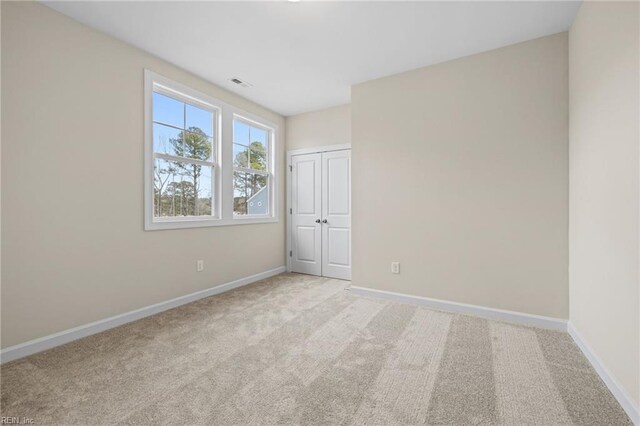 unfurnished bedroom with a closet, visible vents, baseboards, and carpet floors