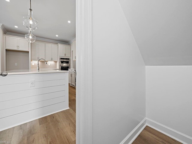 kitchen featuring light countertops, wood finished floors, baseboards, and backsplash