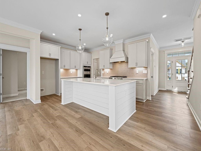 kitchen featuring crown molding, custom range hood, light countertops, and a sink