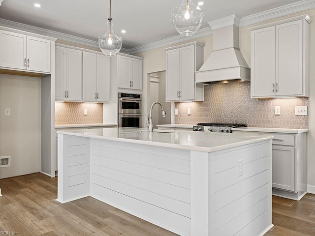 kitchen with custom range hood, ornamental molding, stove, stainless steel double oven, and a sink