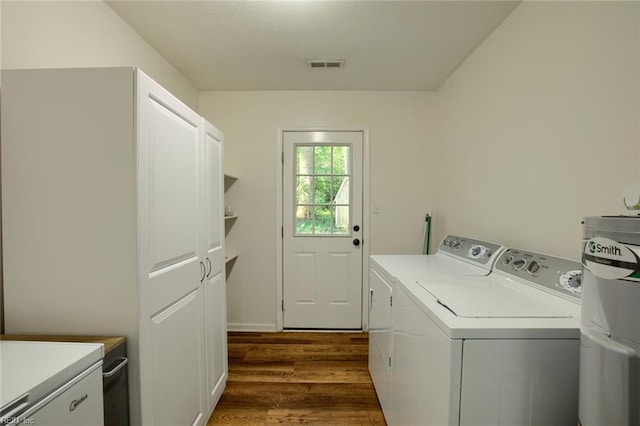 laundry room featuring water heater, dark hardwood / wood-style flooring, independent washer and dryer, and cabinets