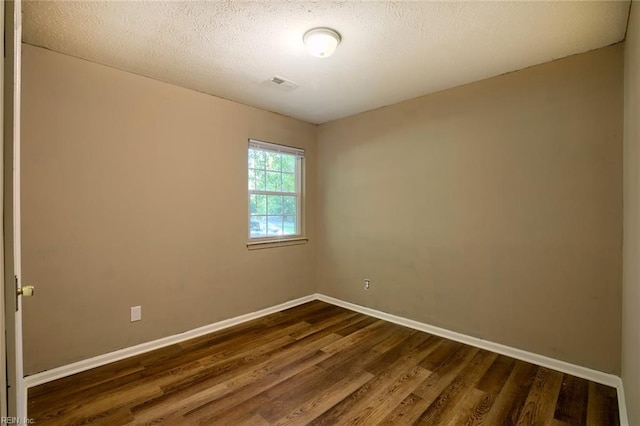 empty room featuring a textured ceiling and dark hardwood / wood-style floors