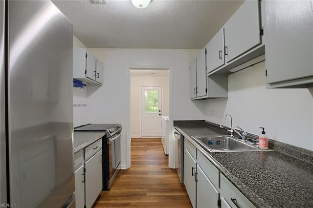 kitchen with a textured ceiling, appliances with stainless steel finishes, hardwood / wood-style flooring, and sink