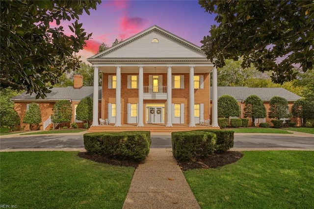 neoclassical home with a balcony and a lawn