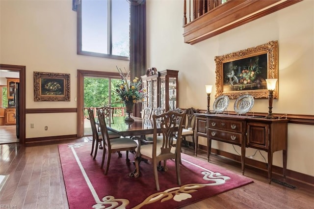 dining space featuring hardwood / wood-style flooring and a towering ceiling