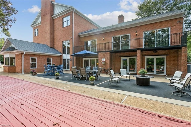 back of house featuring a patio, a balcony, a deck, and a fire pit