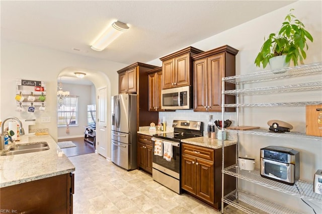 kitchen featuring light stone countertops, sink, stainless steel appliances, and tasteful backsplash