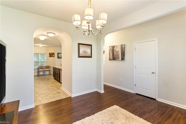 unfurnished dining area featuring a chandelier and dark hardwood / wood-style flooring