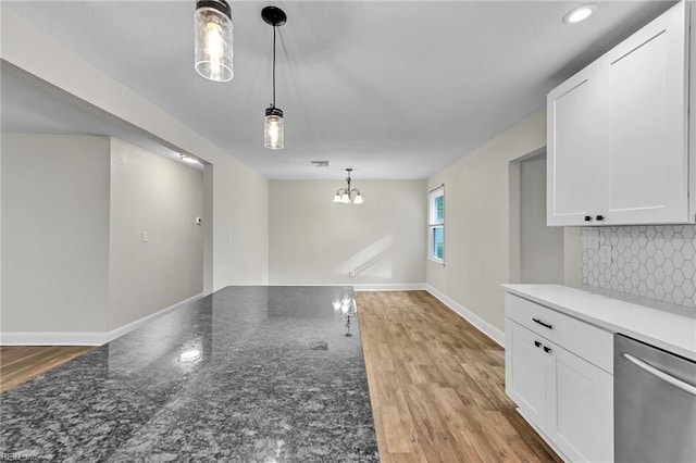 interior space with an inviting chandelier, hanging light fixtures, dishwasher, and white cabinets