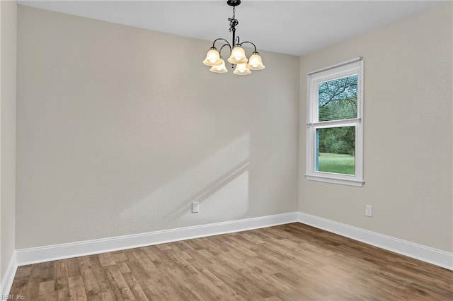 spare room with hardwood / wood-style flooring and a notable chandelier