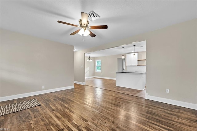 unfurnished living room with ceiling fan with notable chandelier and dark hardwood / wood-style floors