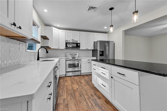 kitchen with tasteful backsplash, sink, white cabinetry, stainless steel appliances, and dark hardwood / wood-style flooring