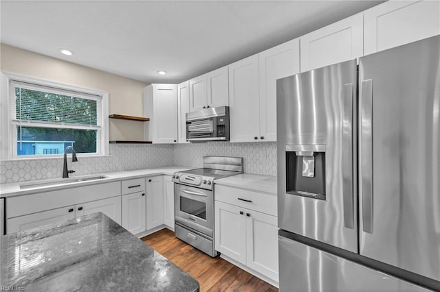 kitchen with appliances with stainless steel finishes, tasteful backsplash, sink, and white cabinets