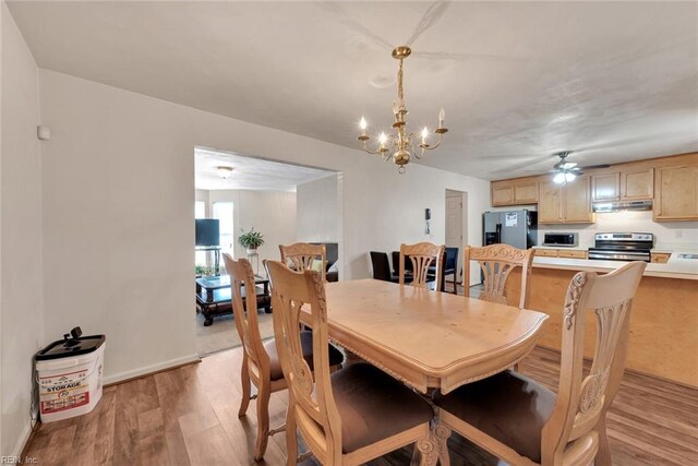 dining room with ceiling fan with notable chandelier and light hardwood / wood-style flooring