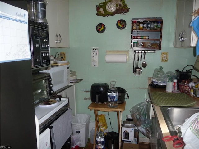 kitchen featuring refrigerator and white cabinetry