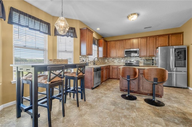 kitchen featuring a breakfast bar, decorative light fixtures, stainless steel appliances, and a kitchen island