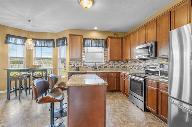 kitchen featuring a breakfast bar area, decorative backsplash, decorative light fixtures, a kitchen island, and stainless steel appliances