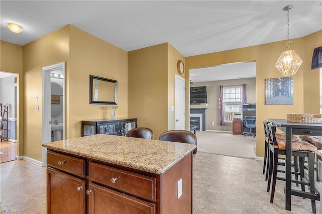 kitchen featuring light stone countertops, a center island, an inviting chandelier, pendant lighting, and light carpet