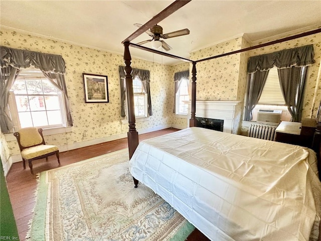 bedroom featuring hardwood / wood-style floors, cooling unit, crown molding, ceiling fan, and radiator heating unit