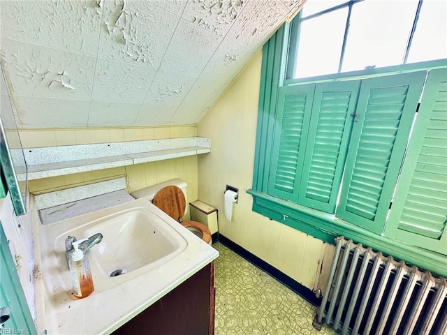 bathroom featuring radiator, vanity, and vaulted ceiling