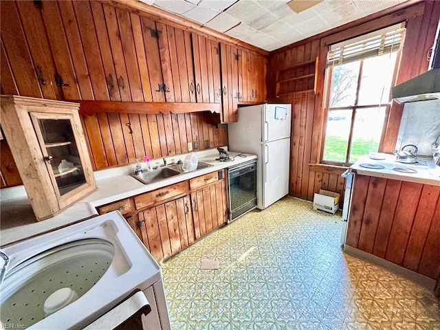 kitchen with wooden walls, stove, white refrigerator, and sink