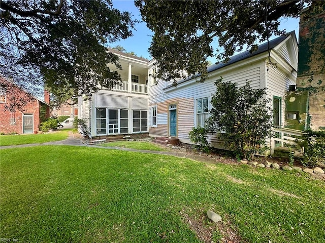 rear view of property with a yard and a balcony