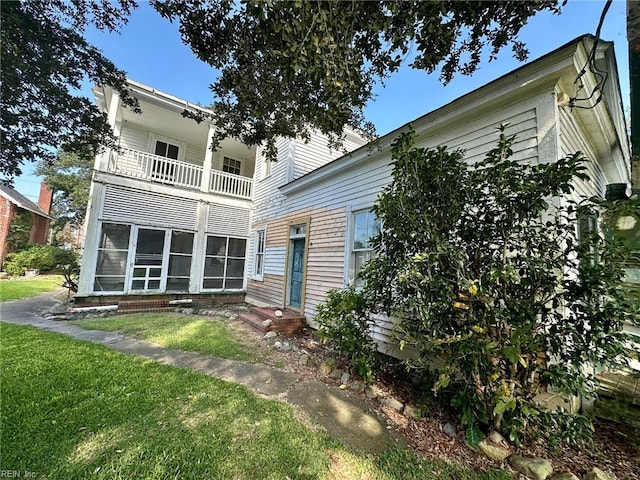 back of property with a balcony and a yard