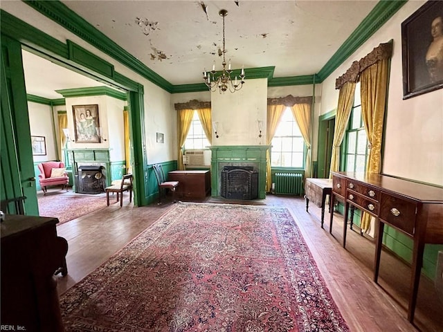 sitting room featuring hardwood / wood-style floors, ornamental molding, radiator, and an inviting chandelier