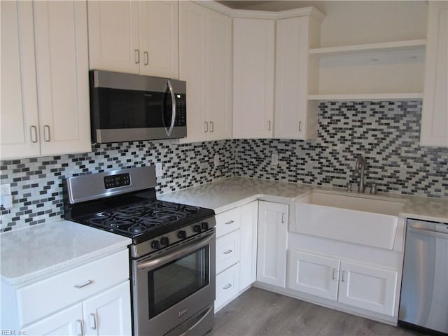 kitchen featuring backsplash, light hardwood / wood-style floors, appliances with stainless steel finishes, and white cabinetry