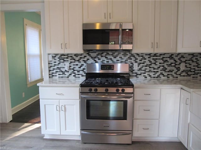 kitchen with backsplash, white cabinetry, stainless steel appliances, dark hardwood / wood-style floors, and light stone countertops