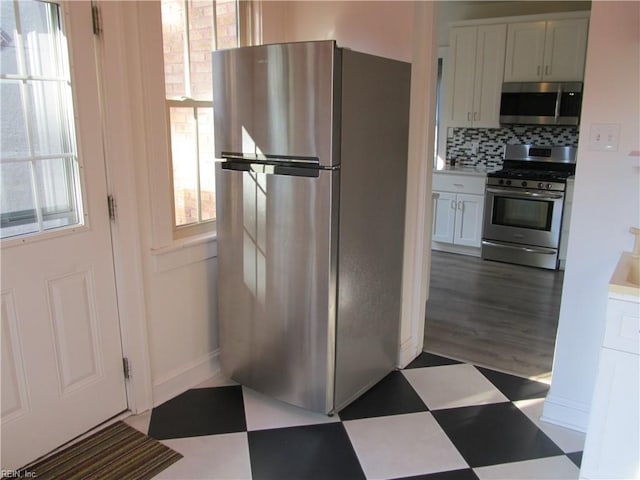 kitchen with stainless steel appliances, tasteful backsplash, and white cabinetry